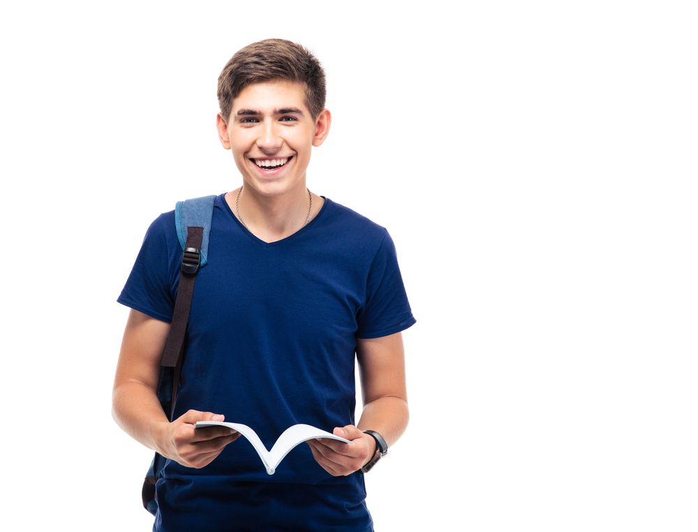 Happy male student standing and holding book isolated on a white background. Looking at camera
